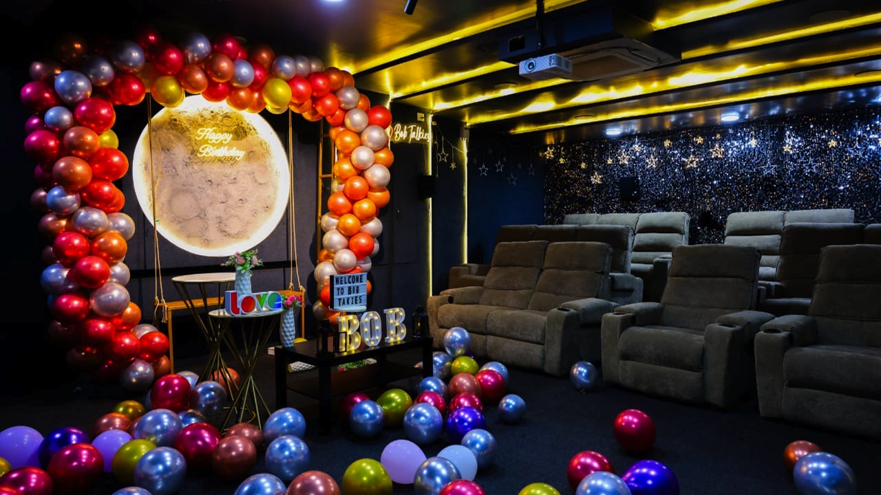 Private theatre with birthday celebration setup, colorful balloon arch, glowing backdrop, comfortable recliner seats, and decorative lighting for a special event experience.